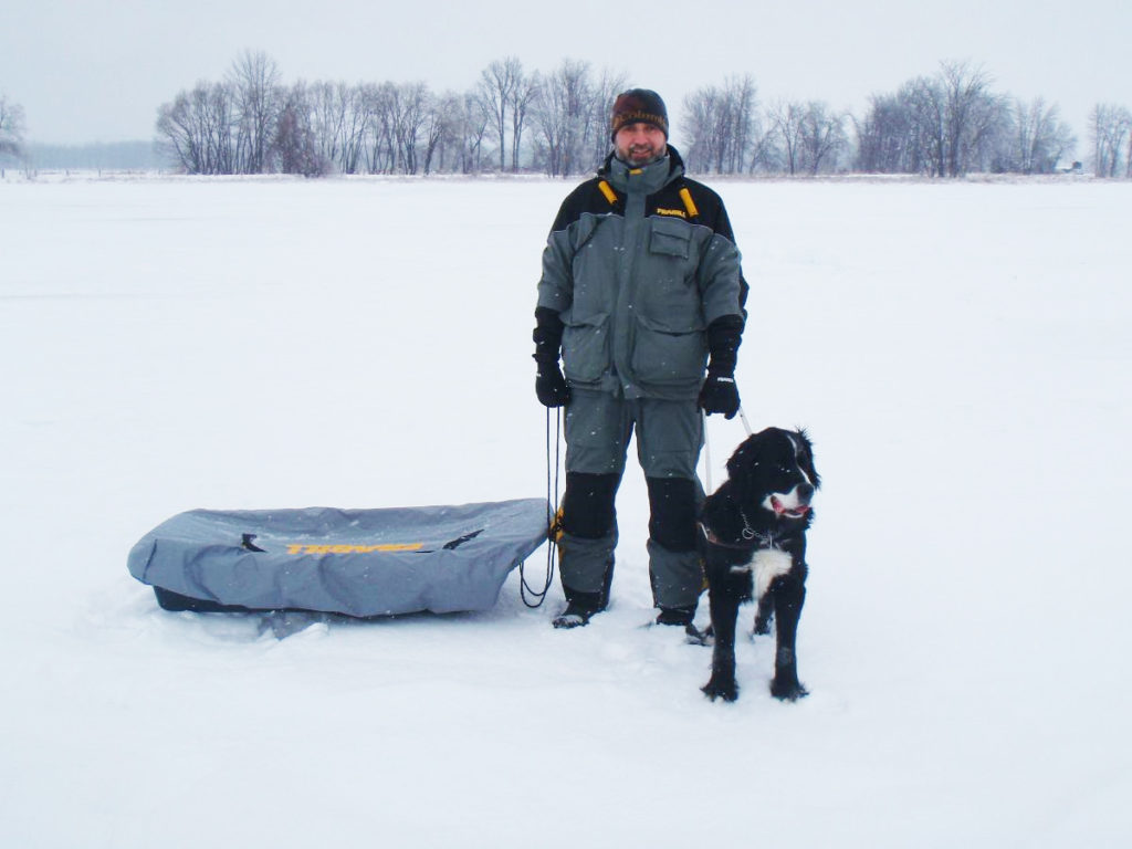 Man with dog and sled on snowy field